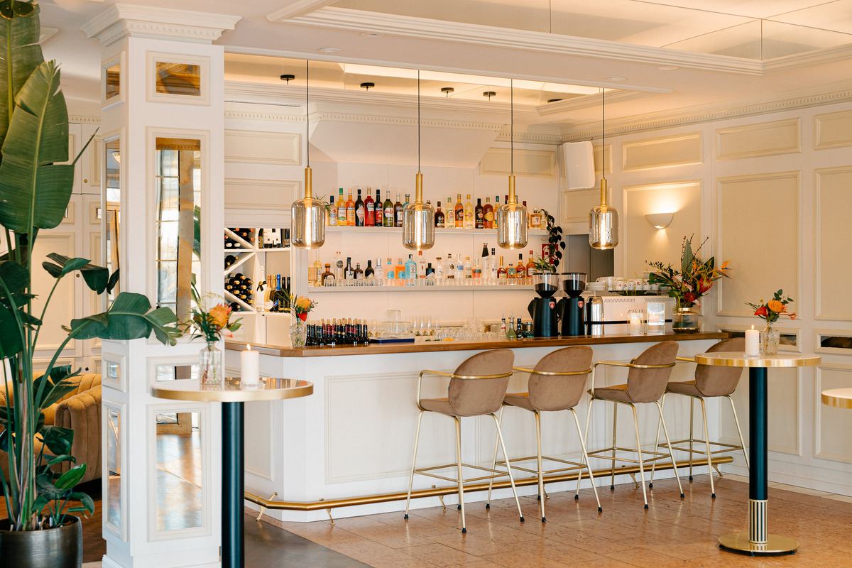 Bar im Deichgraf mit Spirituosenregal, Pendelleuchten, Barhockern und Blumenschmuck