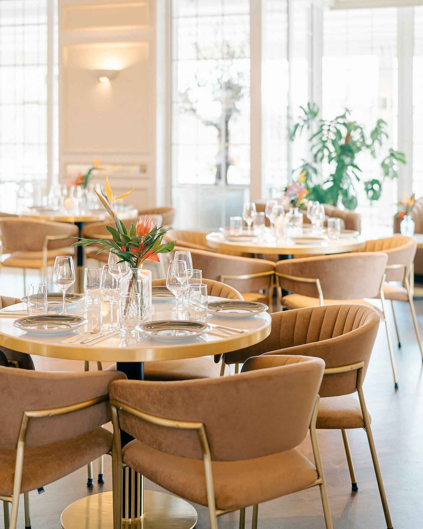 Runde Tische mit goldenen Stuhlbeinen und Blumenschmuck, gedeckt für ein Dinner im Deichgraf