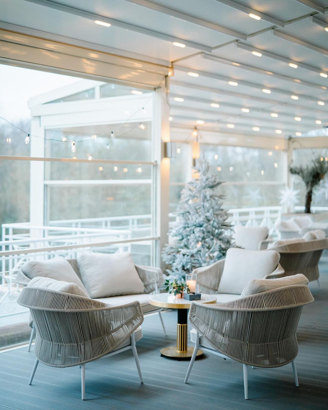 Winterlich dekorierter Wintergarten des Deichgraf mit weißem Weihnachtsbaum, Lichterketten und Korbsesseln